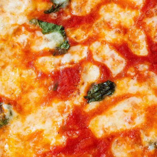 Pizza margherita appena sfornata, con pomodoro, mozzarella filante e foglie di basilico